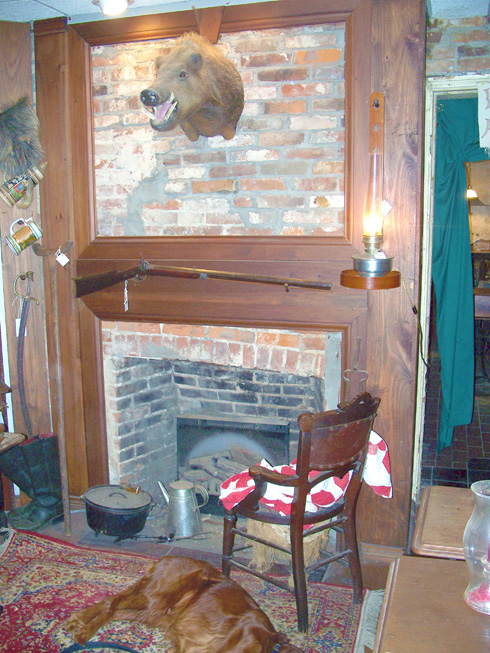 Red Dog Arms, pictures of wild boar head mounted above the fire place and a revolutionary war era musket rifle, dutch oven, and sleeping dog.